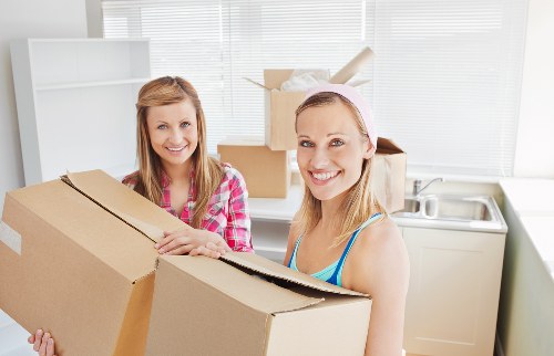 Movers carrying household items from a Stepney flat with stair access